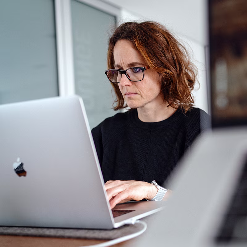 Adina Mugrauer bereitet eine Präsentation am Laptop vor. Sie blickt konzentriert auf den Bildschirm.