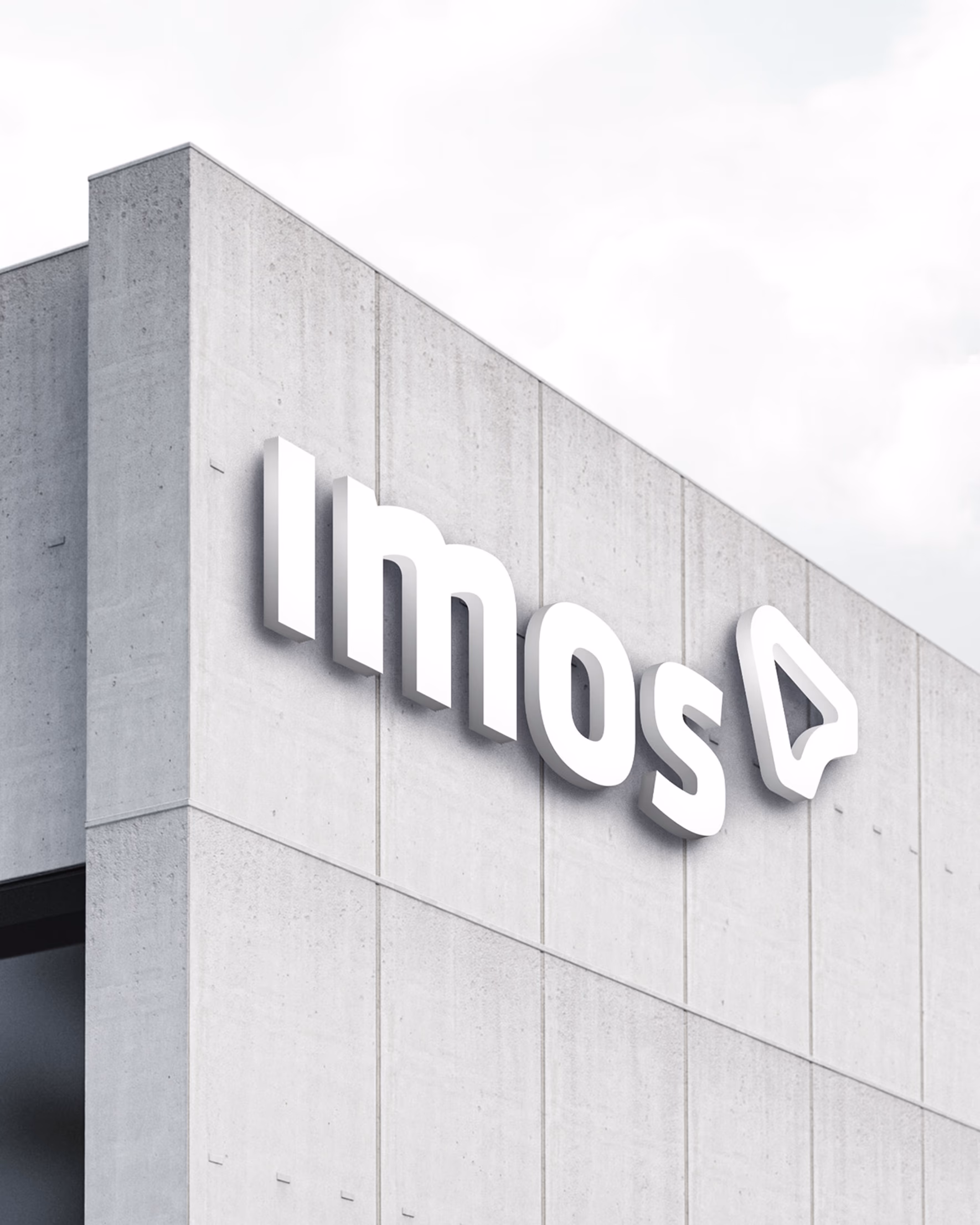 Beleuchtetes 3D-Logo „imos” an einer Betonfassade