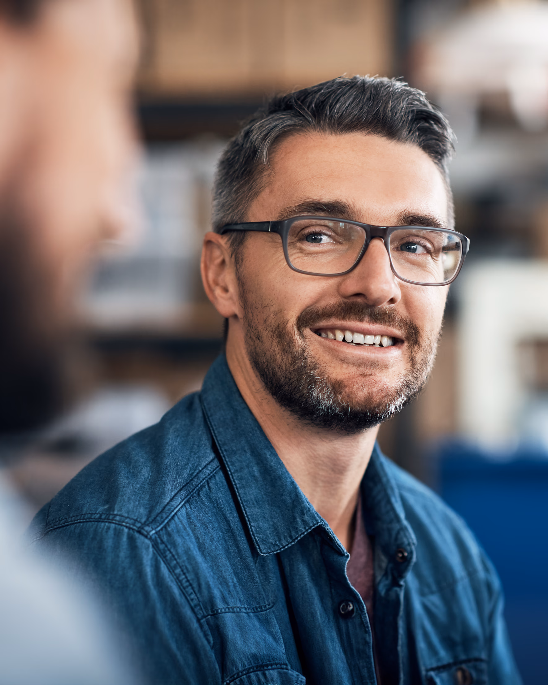 Porträt eines lächelnden Mannes mit Brille im Gespräch